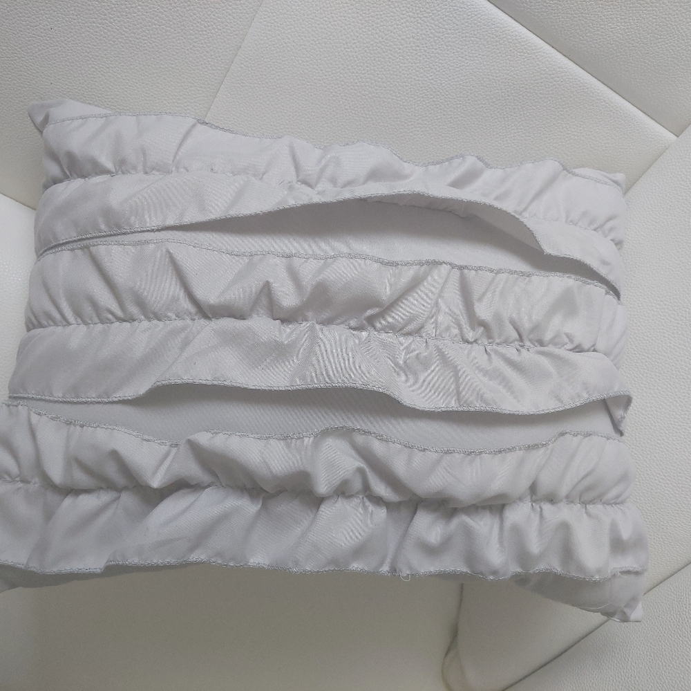 Light gray decorative throw pillow with ruffles.
